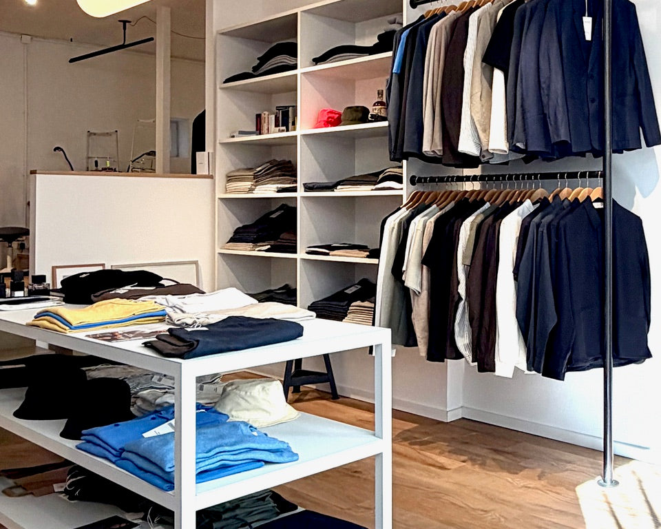Clothing store interior with shelves and racks displaying various garments.